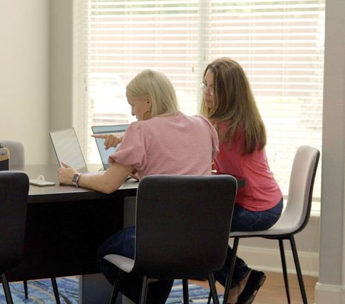 Two people in an office working together on laptops.