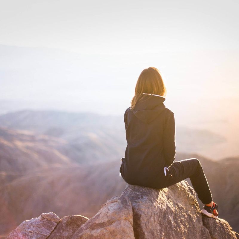 Une femme assise au sommet d'une montagne.